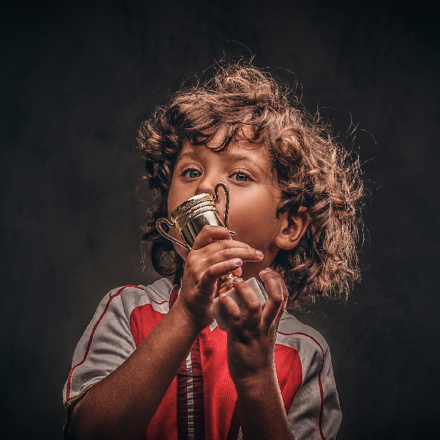 a boy kissing spelling bee winner’s trophy holding in his hand. 